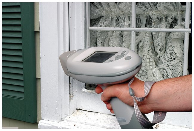 Person using portable analyser on window frame