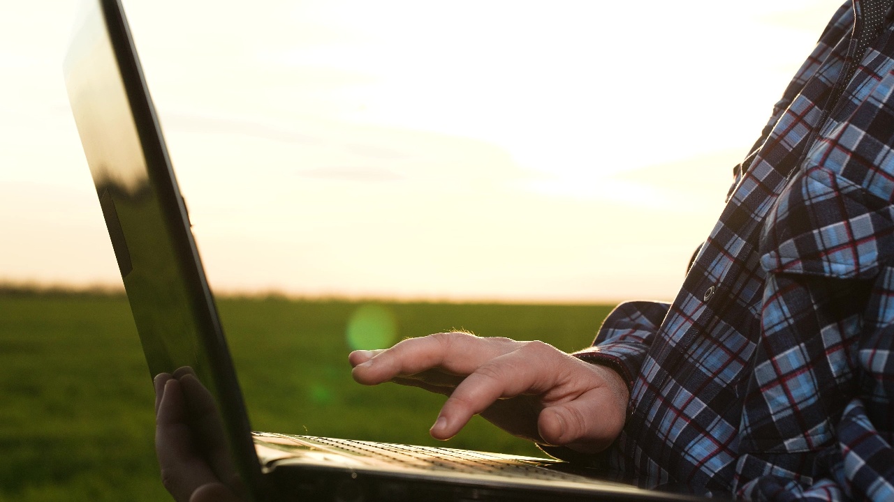 Practical Precision: How Ground-Based Spectral Imaging Brings Crop Monitoring Within Reach 1 Farmer using laptop in a field to analyse crops with precision agriculture tools and ground-based spectral imaging technology.